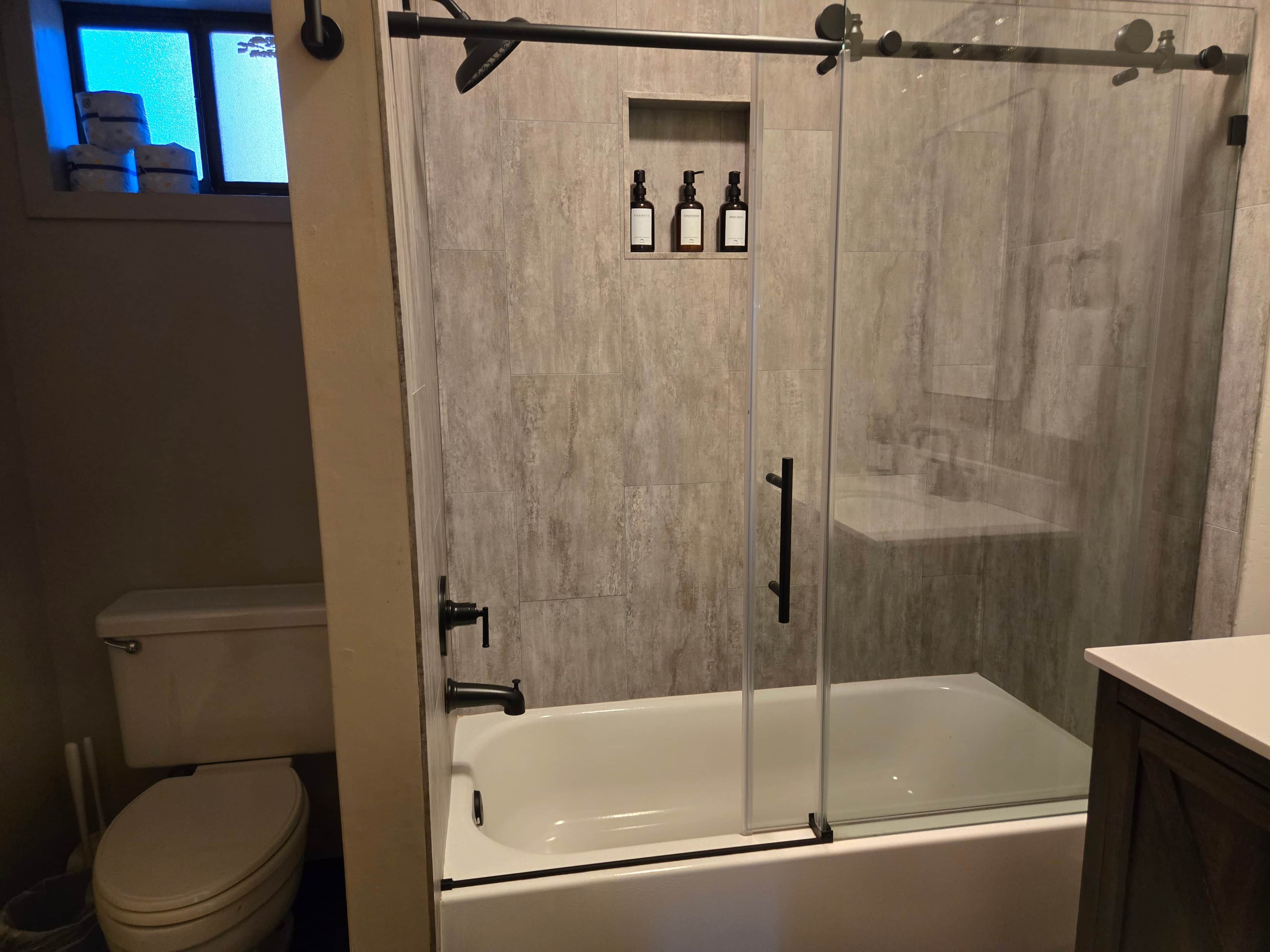 Une salle de bain moderne avec une douche à parois de verre, une baignoire blanche et des toilettes.