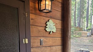 A wooden door with a metal latch, a wall-mounted light fixture, and a wooden sign with text.