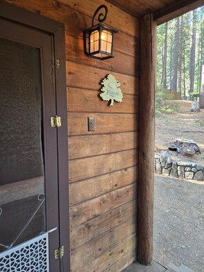 A wooden door with a metal latch, a wall-mounted light fixture, and a wooden sign with text.