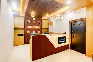 A reception area with a wooden reception desk, a clock, and a wall-mounted air conditioning unit.