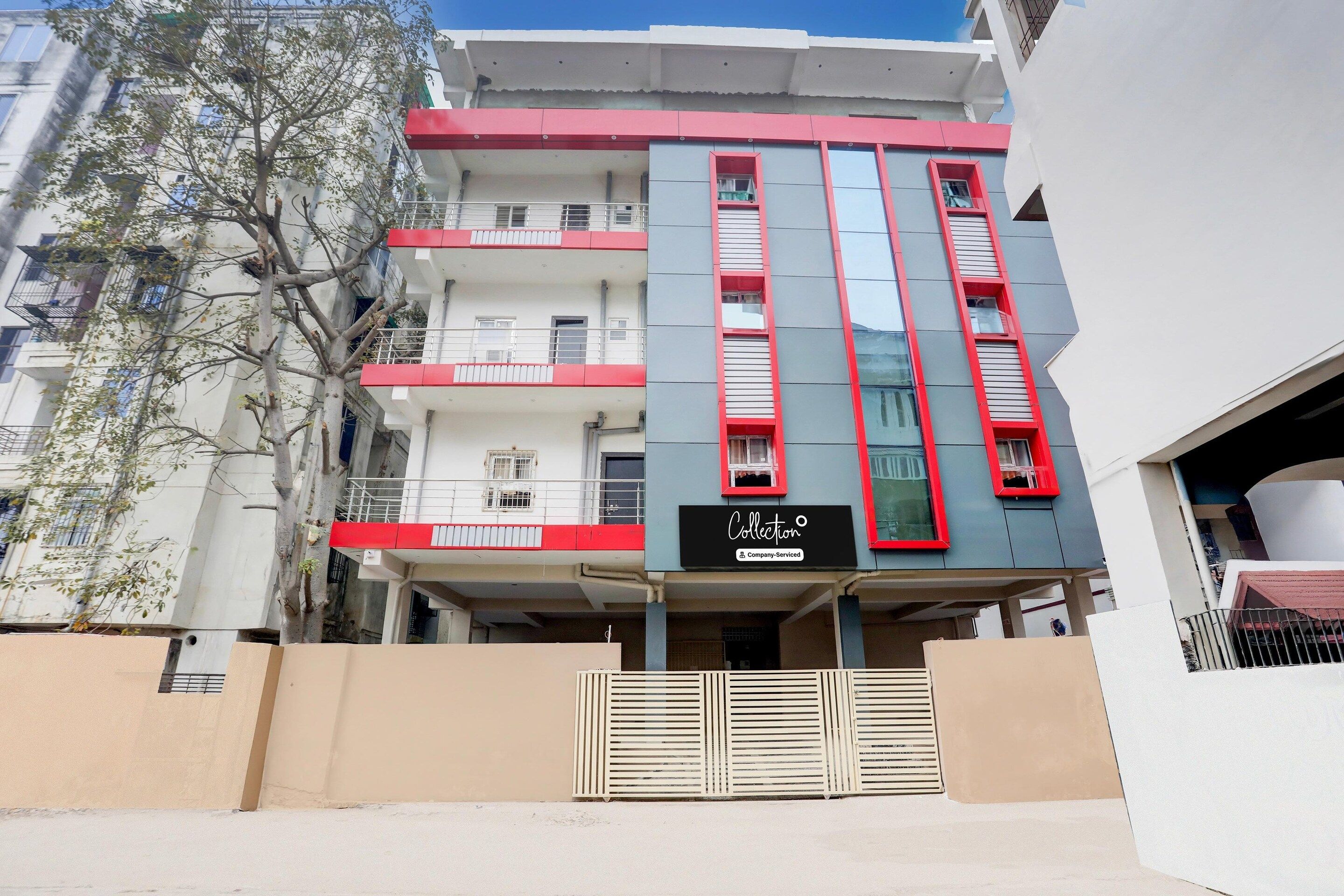 A multi-story building with a red and white facade, balconies, and a sign indicating 'Collection Company-Serviced'.