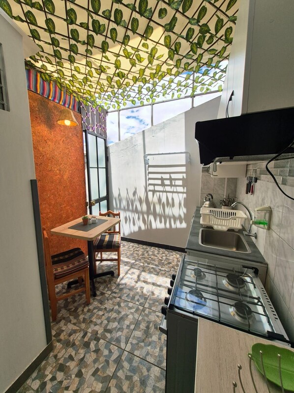A compact kitchen with a gas stove, a sink, and a dining area with a table and chairs.
