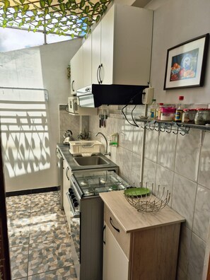A compact kitchen with a gas stove, a sink, and a microwave.