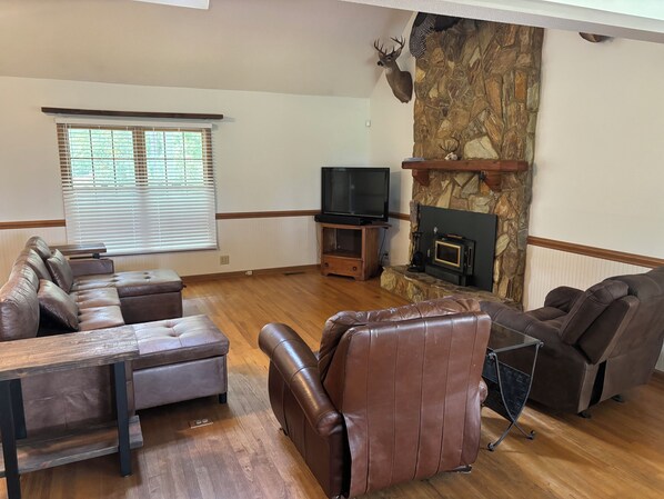 A living room with a stone fireplace, leather sofas, a wooden coffee table, and a television.