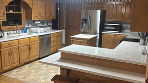 A kitchen with wooden cabinets, a stainless steel refrigerator, a microwave, and a sink. - Perfect 3-bedroom farmhouse with AC in pleasant Washington (Washington)