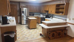 A kitchen with wooden cabinets, a stainless steel refrigerator, a microwave, and a sink. - Perfect 3-bedroom farmhouse with AC in pleasant Washington (Washington)