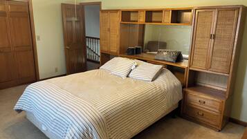 Une chambre à coucher avec un lit, une armoire en bois et un ventilateur de plafond.