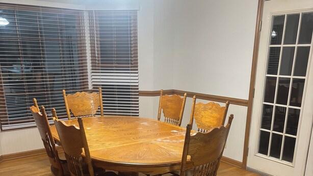 A dining area with a round wooden table surrounded by six chairs, a ceiling fan, and a window with blinds. - Perfect 3-bedroom farmhouse with AC in pleasant Washington (Washington)