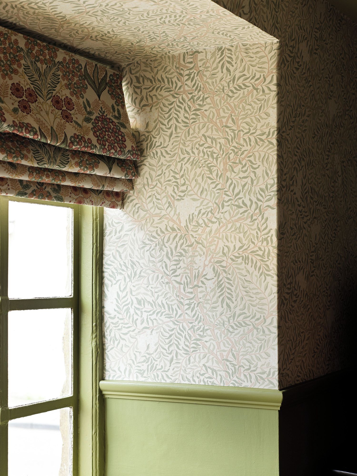 A room corner with patterned wallpaper and a window with a green trim.