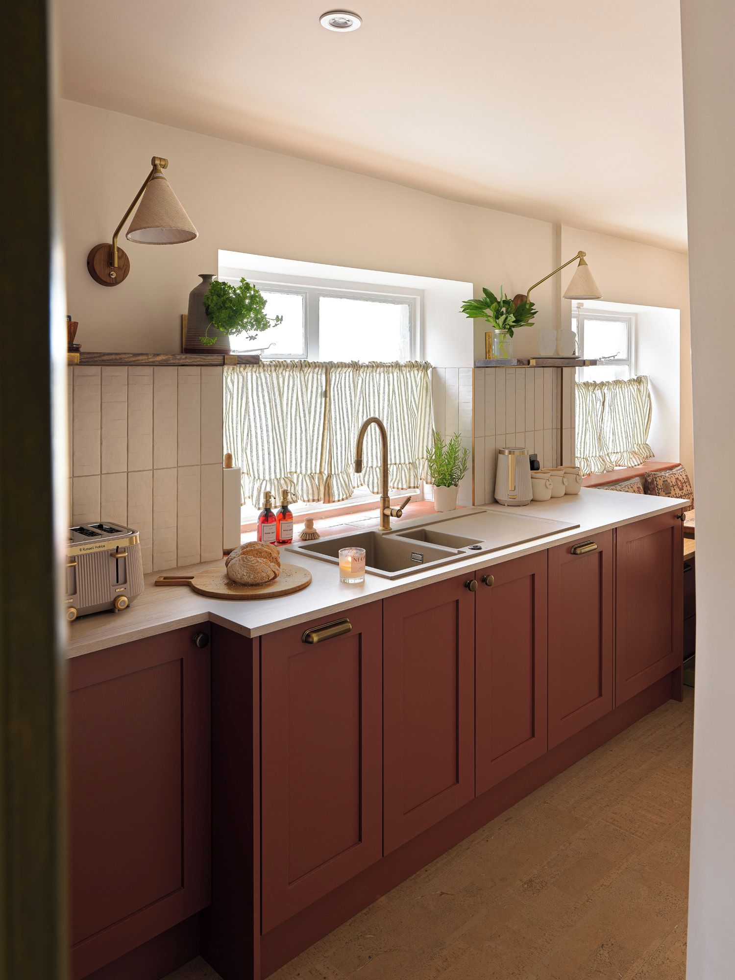 A kitchen with a large island, a sink, and a window with curtains.