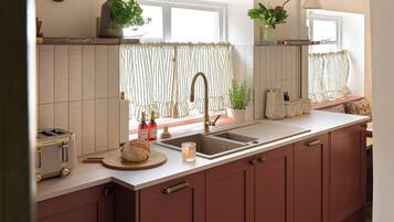 A kitchen with a large island, a sink, and a window with curtains.