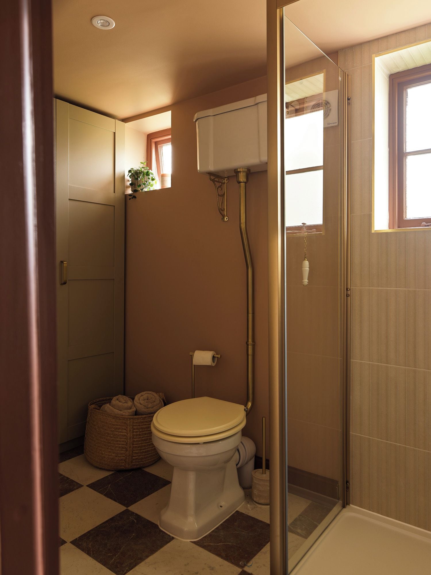 A bathroom with a toilet, bidet, and shower. There is a window with a view of the outside.