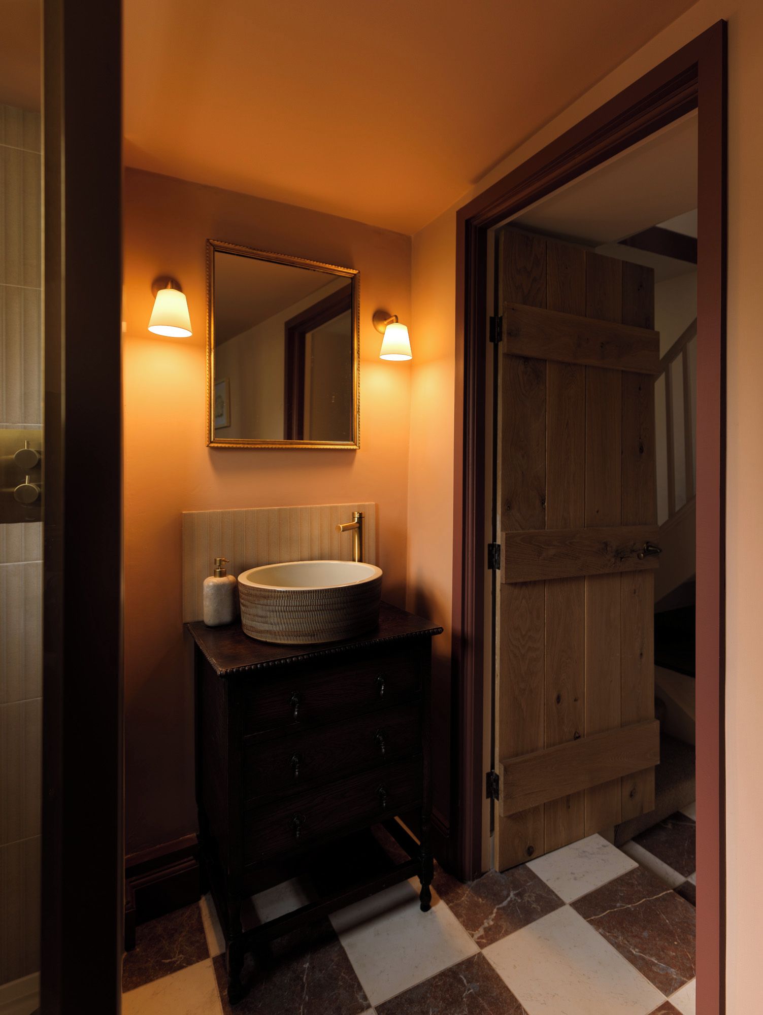 A bathroom with a round sink, a mirror, and two wall-mounted lights.