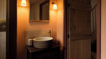 A bathroom with a round sink, a mirror, and two wall-mounted lights.