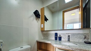 Ein Badezimmer mit Toilette, Waschbecken, Spiegel und Handtuchhalter.