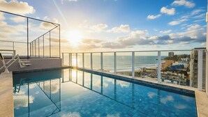 Ein Dachpool mit Infinity-Kante und freiem Blick auf das Meer und die Stadtlandschaft.