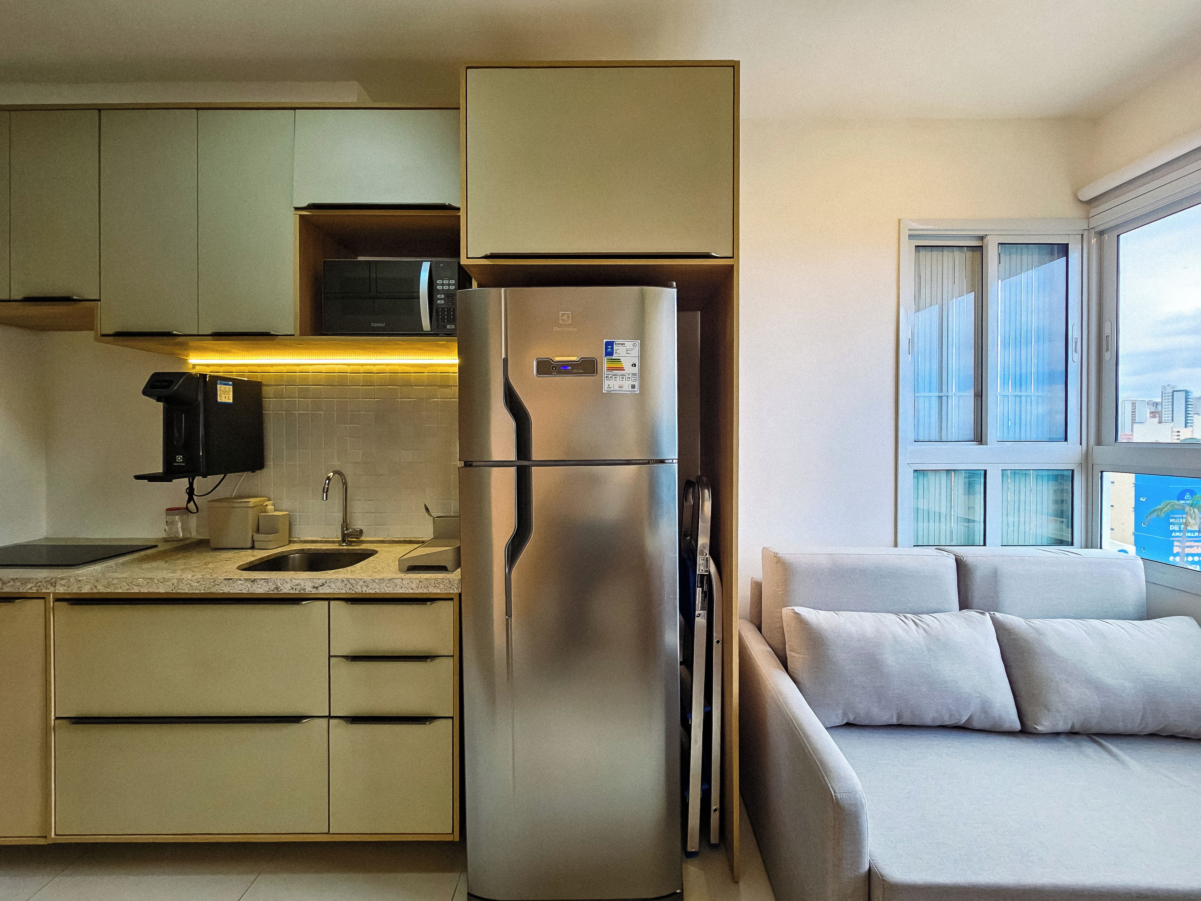 A compact kitchen with a built-in refrigerator, a microwave, and a coffee machine.