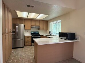 A kitchen with a stainless steel refrigerator, a microwave, a stove, and wooden cabinets. - 3b2b single story house in beautiful Chino with New kitchen/Ping-Pong table/WIFI (Chino)