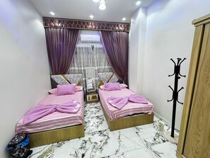 A bedroom with two beds, a coat rack, and an air conditioning unit. - The "Villa of Dreams VIP" is reserved exclusively for families. The renter is required to provide a security deposit, which will be refunded upon checkout. (Giza Governorate)