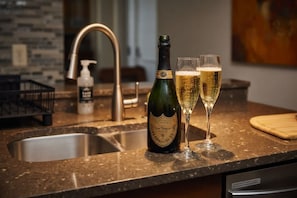 Un comptoir de cuisine avec une bouteille de champagne et deux verres remplis de champagne.
