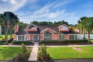 Une maison à deux étages avec un porche à l’avant, un garage et une pelouse bien entretenue.