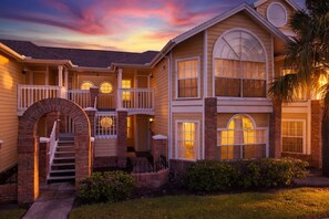 A two-story house with a front porch, a staircase, and a garage. - Whimsical Wonders Sweetwater Club Near Disney (Kissimmee)