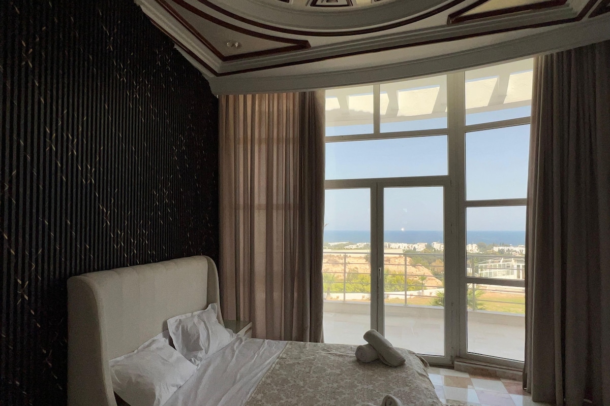 Une chambre avec une grande fenêtre, un lit et une vue sur le paysage urbain.