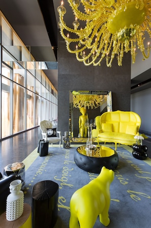 Ein modernes Interieur mit einem gelben Sofa, einer reflektierenden Skulptur und einem Chandelier.