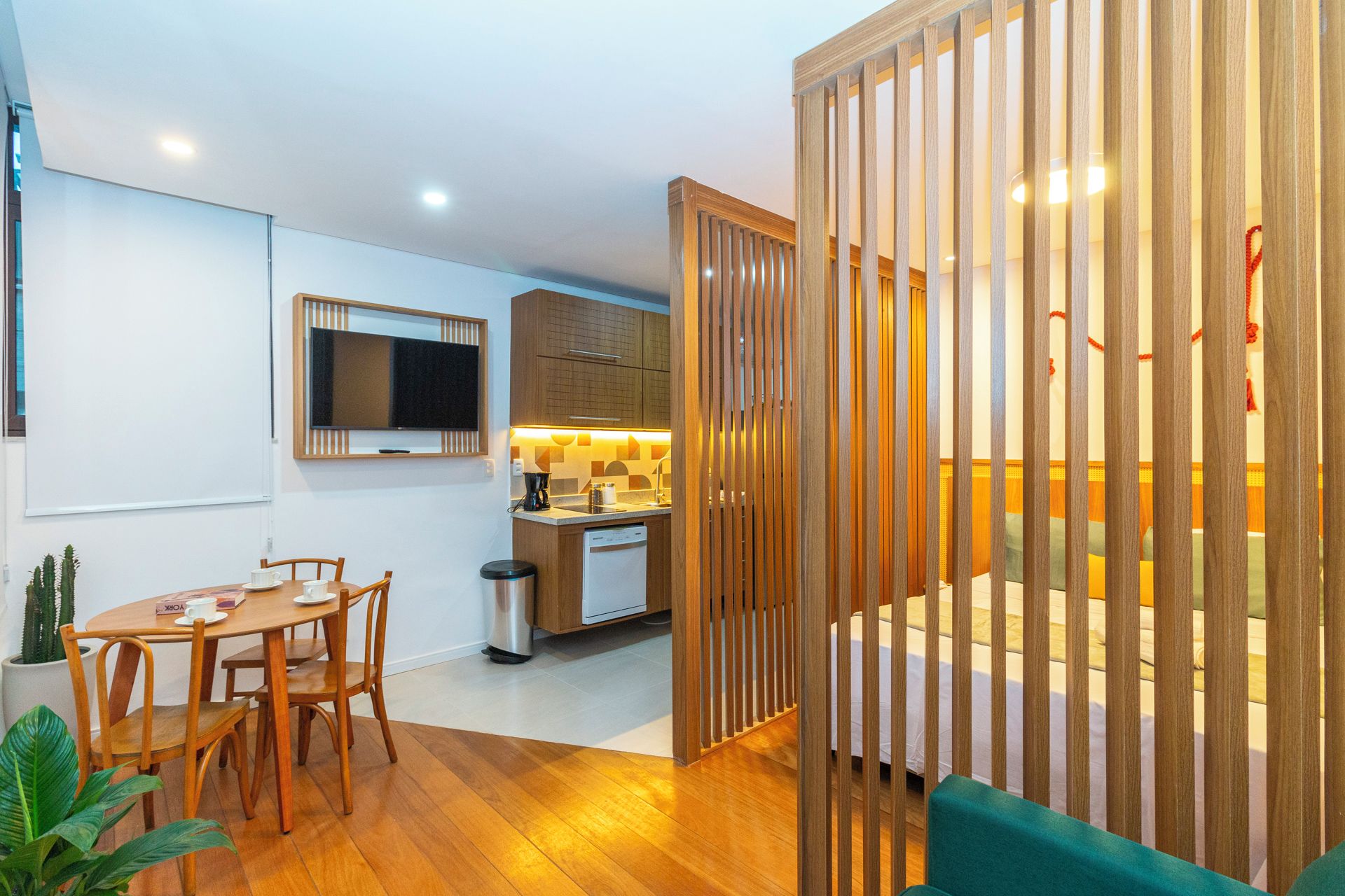 A compact living space with a kitchenette, a dining area, and a sleeping area separated by a wooden partition.