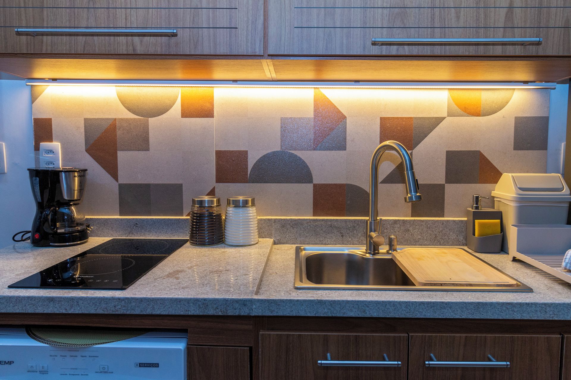 A modern kitchen with a built-in stove, a sink, and a coffee maker.