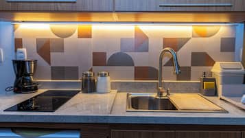 A modern kitchen with a built-in stove, a sink, and a coffee maker.
