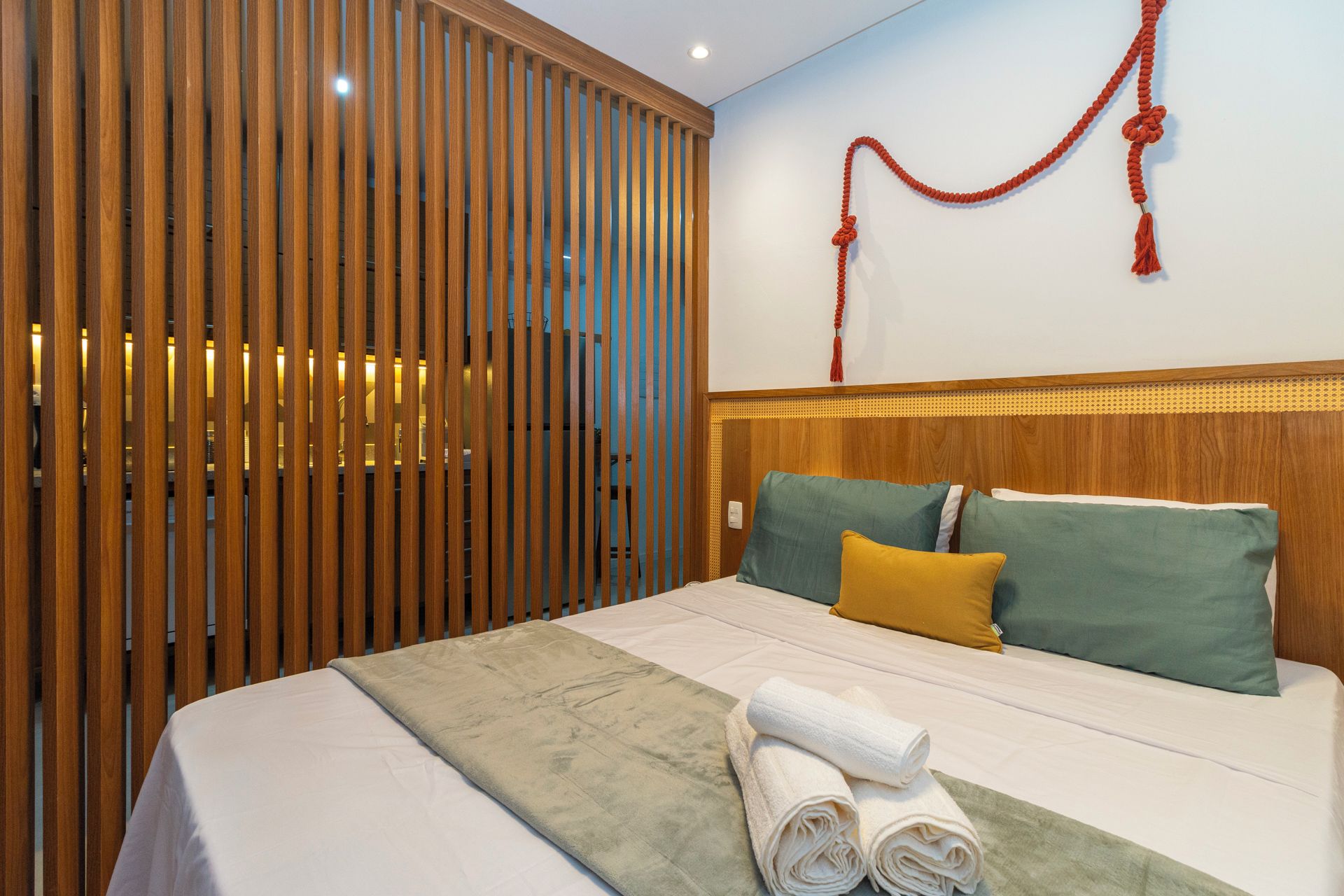 Una habitación de hotel con una cama, un panel de madera y una pared con un adorno rojo.