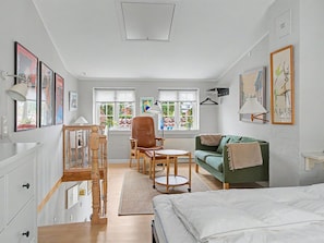 A spacious room with a bed, a green sofa, a brown chair, a small table, and a staircase. - "Lutz" - 275m from the sea by Interhome (Faaborg)