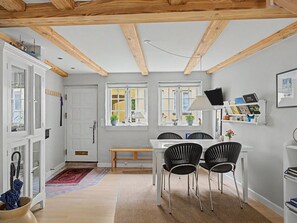 Une cuisine compacte avec un coin repas, dotée d’un plafond en bois, de meubles blancs et d’une petite table à manger avec des chaises.