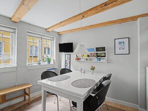 A dining area with a white table, black chairs, a bench, a TV, and a shelf with books and decorative items. - "Lutz" - 275m from the sea by Interhome (Faaborg)