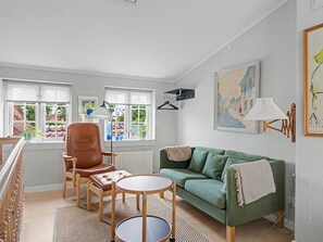 A room with a green sofa, a brown leather chair, a small round table, and a radiator. - "Lutz" - 275m from the sea by Interhome (Faaborg)