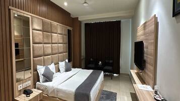 A modern bedroom with a large bed, built-in wardrobe, and a TV on the wall.