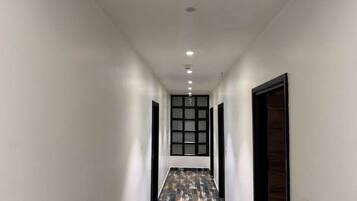 A hallway with a patterned floor, white walls, and a door at the end.