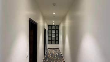 A hallway with a patterned floor, white walls, and a door on the left.