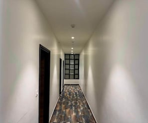 A hallway with a patterned floor, white walls, and a door on the left. - Classic Hotel Mark (Ambala)