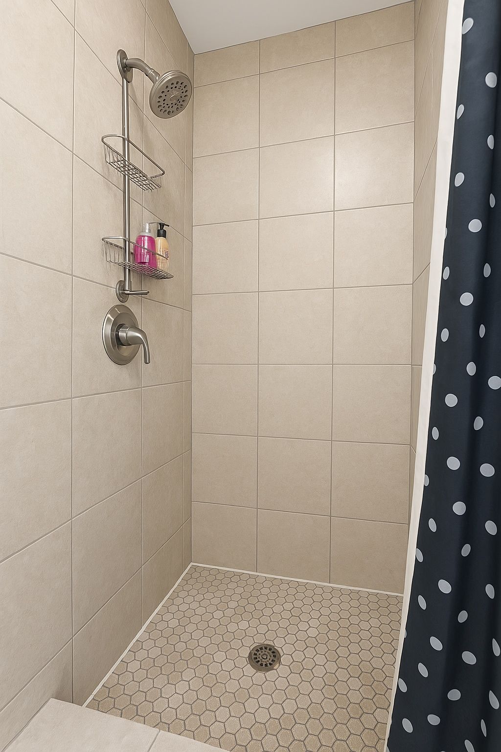 A shower with a rain shower head, a handheld showerhead, and a small shelf with toiletries.