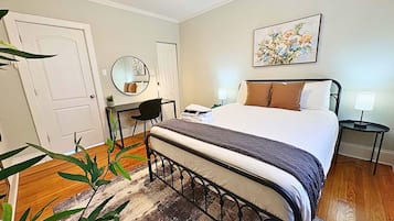 A bedroom with a bed, bedside table, lamp, and a painting on the wall.