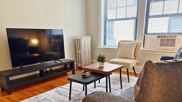 Una sala de estar con una televisión de pantalla plana, una mesa de centro, un sofá y una silla.