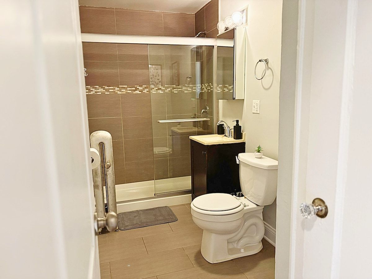 A modern bathroom with a glass-enclosed shower, a white toilet, and a sink with a mirror above it.
