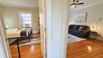 A room with a bed, a window, a radiator, a ceiling fan, and a couch.