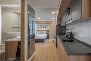 Ein kleines Hotelzimmer mit Küchenzeile, einem Bett und einem Badezimmer.