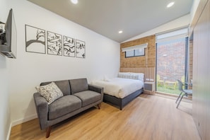 Een moderne slaapkamer met een bank, een bed en een balkon met tuinmeubilair.