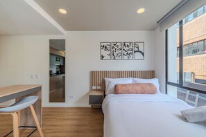Ein modernes Schlafzimmer mit einem Bett, einem Schreibtisch und Blick ins Freie.