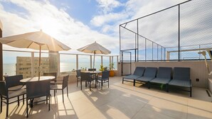 Une terrasse sur le toit, avec des espaces de détente en plein air, des parasols et une vue sur la mer.