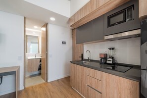 A modern kitchen with wooden cabinets, a built-in microwave, a coffee maker, and a blender. - Studio Bogota 1Bed Sierra Madre (Bogotá)